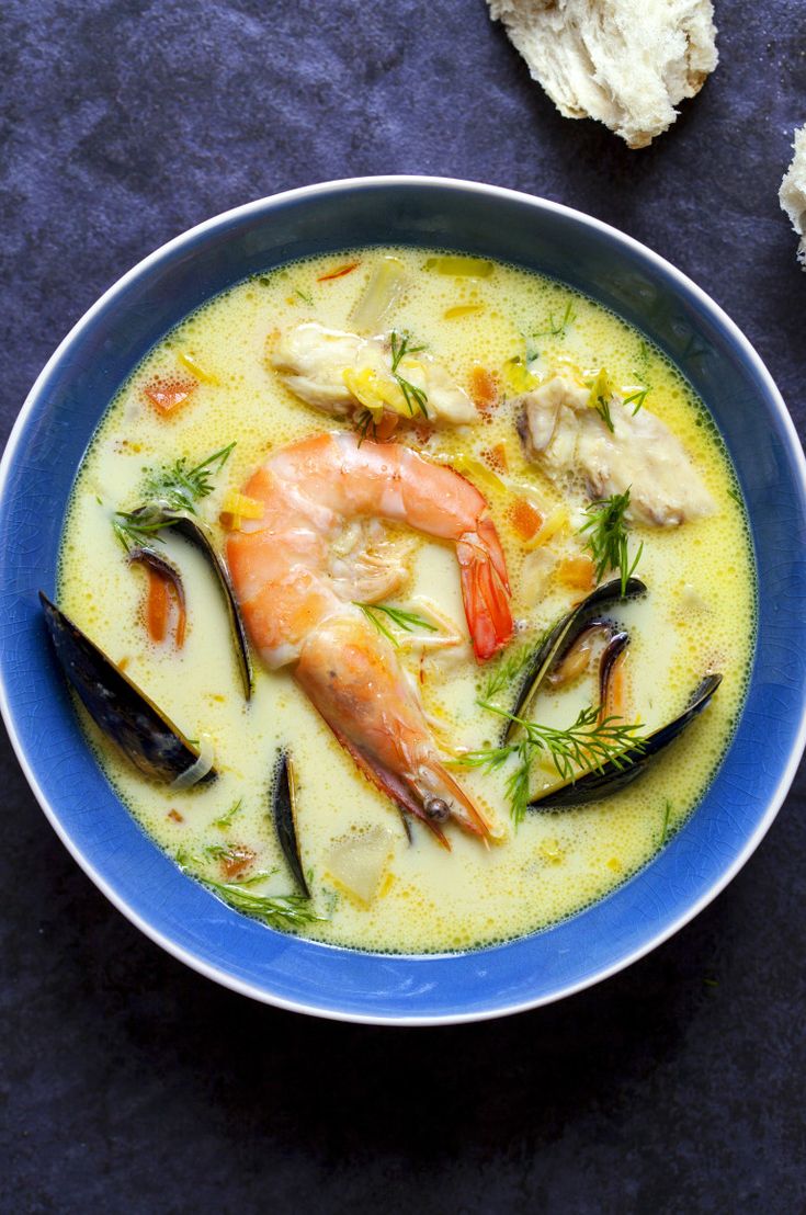 a blue bowl filled with shrimp and mussels on top of a black table