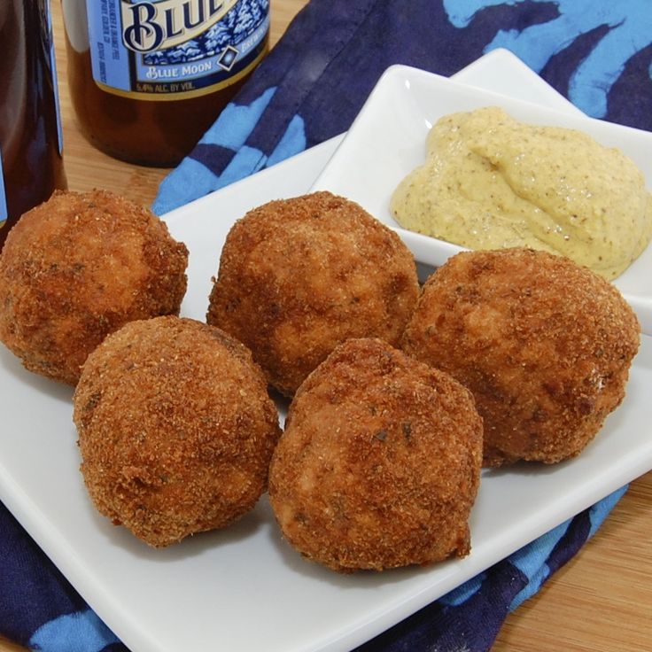 some fried food on a white plate next to a bottle of beer