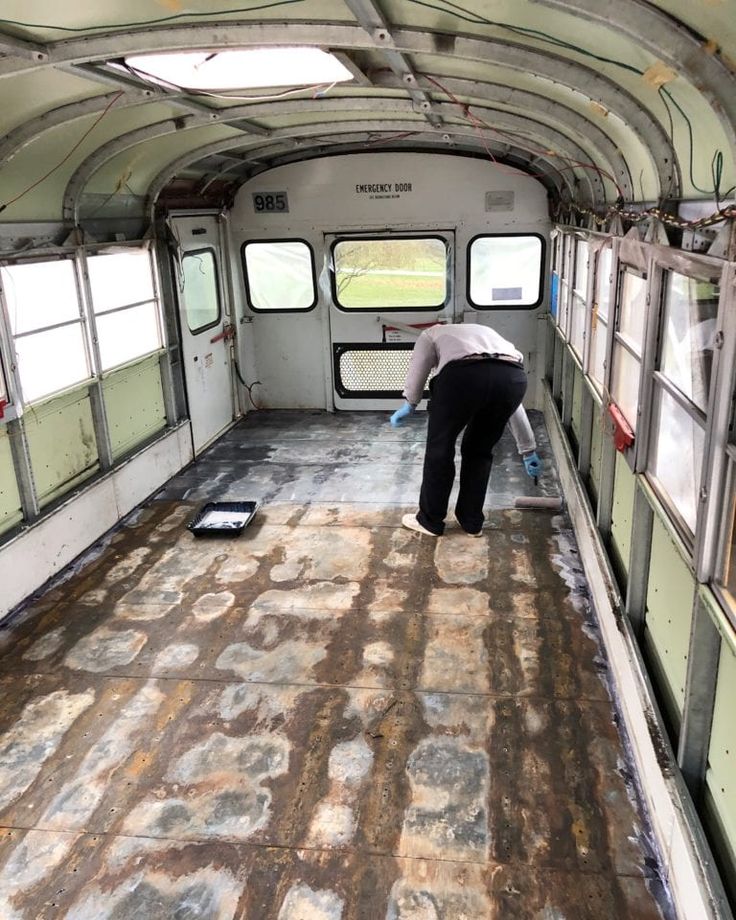 a man is painting the inside of an old bus