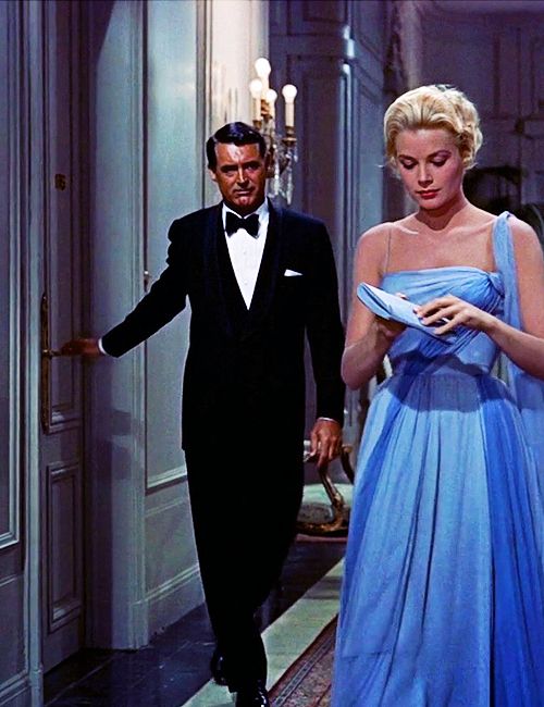 a man in a tuxedo walking next to a woman in a blue dress