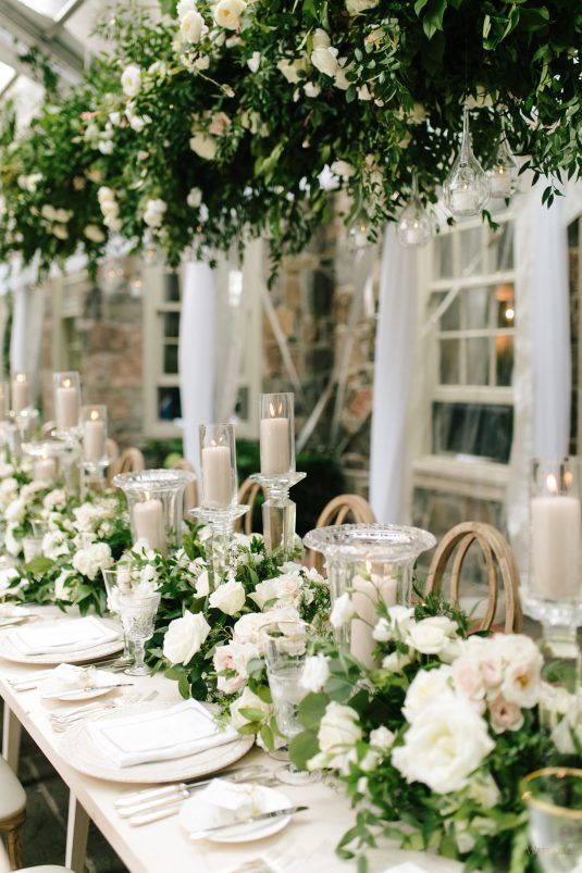 a long table is set with white flowers and candles