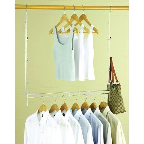 there are many white shirts hanging on the clothes rack in front of a beige wall