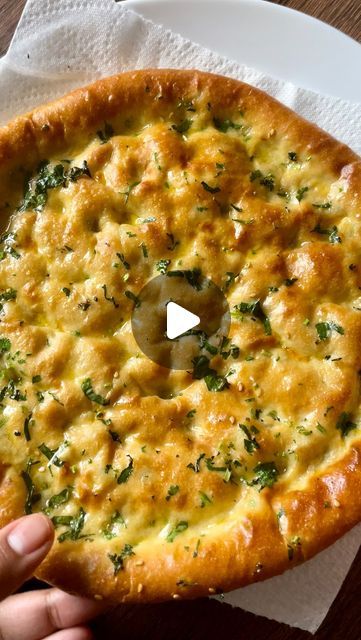 a person holding a pizza on top of a white plate with cheese and parsley