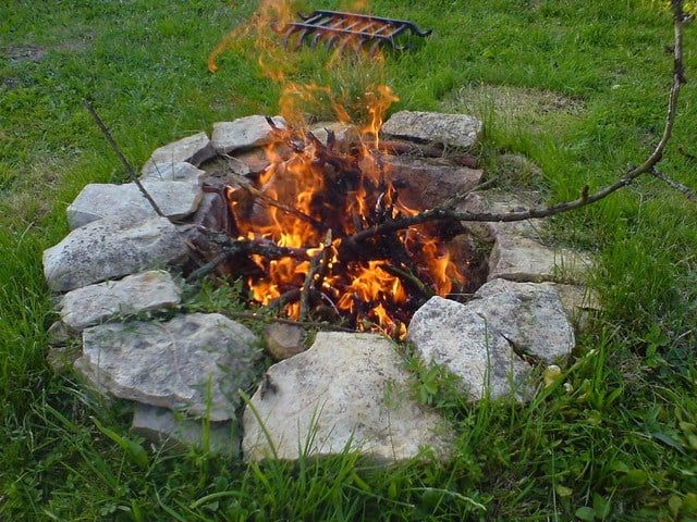 a fire pit made out of rocks in the grass