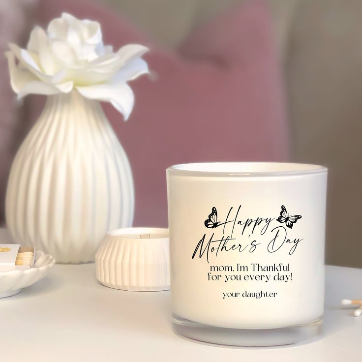 a white candle sitting on top of a table next to a vase with flowers in it