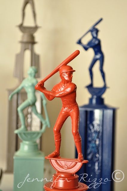 a statue of a man holding a baseball bat on top of a table next to other statues