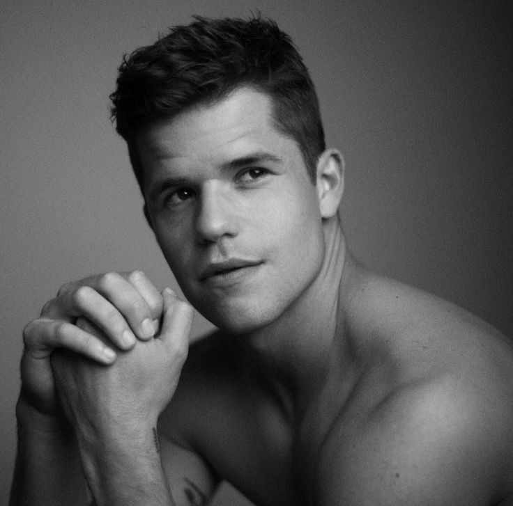 black and white photograph of a shirtless young man with his hand on his chin