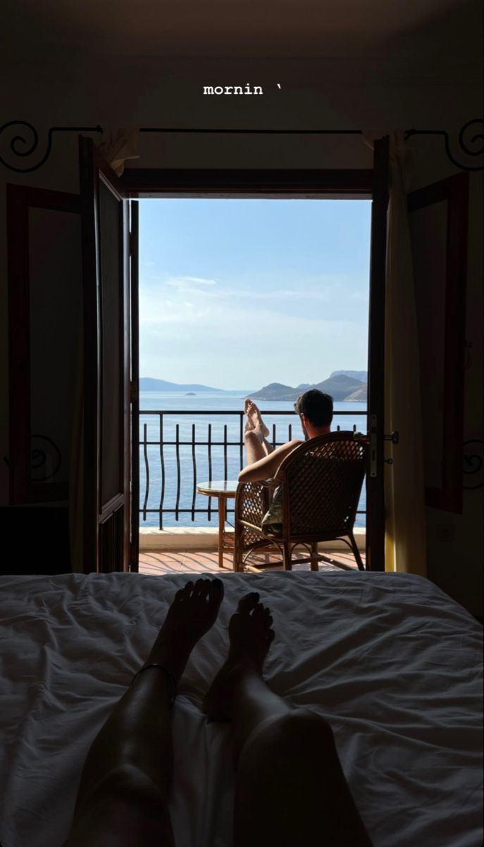 a person sitting in a chair on top of a bed next to an open door