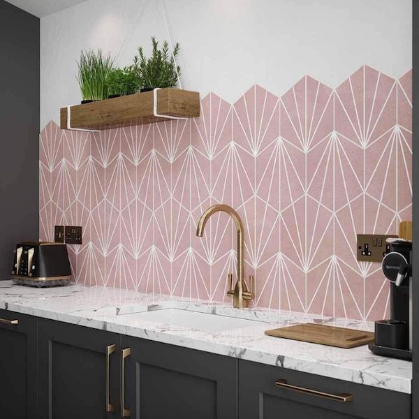 a kitchen with pink and white wallpaper, gold faucet, marble counter tops and black cabinets