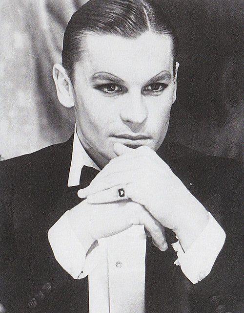 black and white photograph of a man in a tuxedo with his hand on his chin