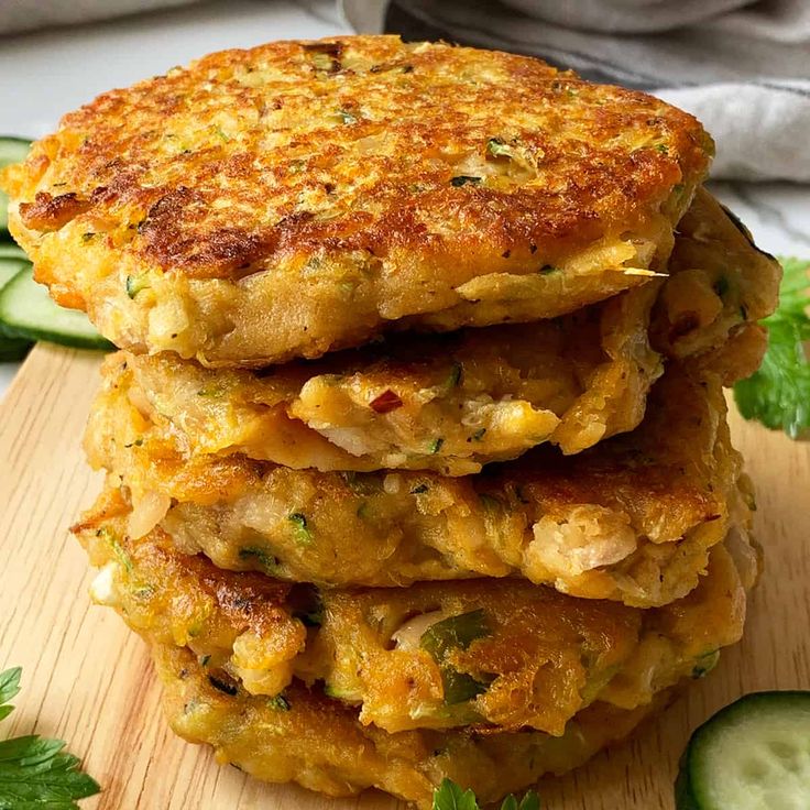 three crab cakes stacked on top of each other with cucumber slices around them