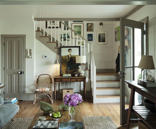 a living room filled with furniture next to a stair case in a white walled house