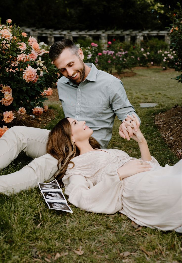 a man and woman laying on the grass in front of some flowers with their eyes closed