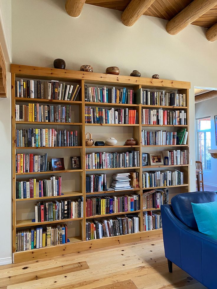 a blue couch sitting in front of a book shelf filled with books