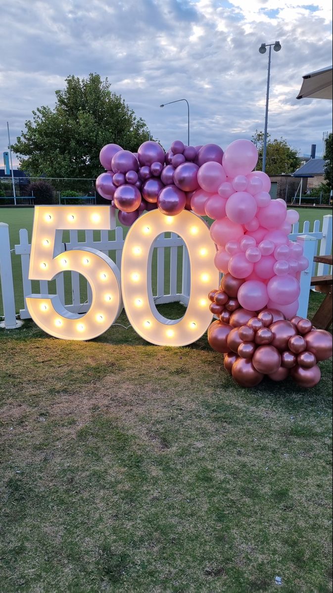 a sign that says 50 with balloons and lights in the shape of numbers on it