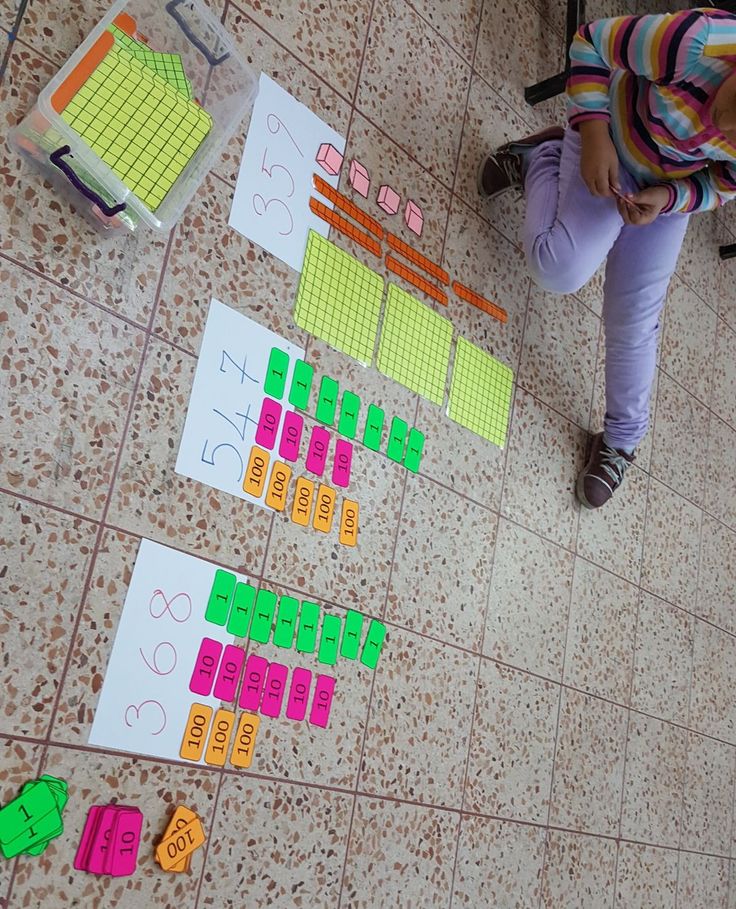 two children are sitting on the floor playing with their numbers and counting puzzles in front of them