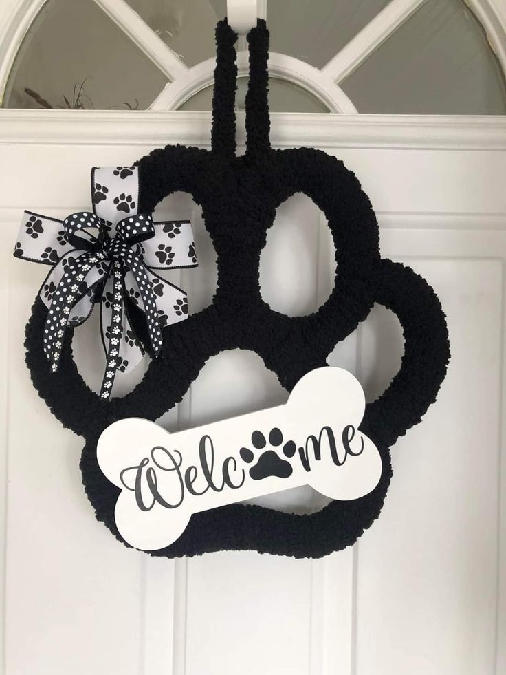 a black and white door hanger that says welcome with a dog bone on it