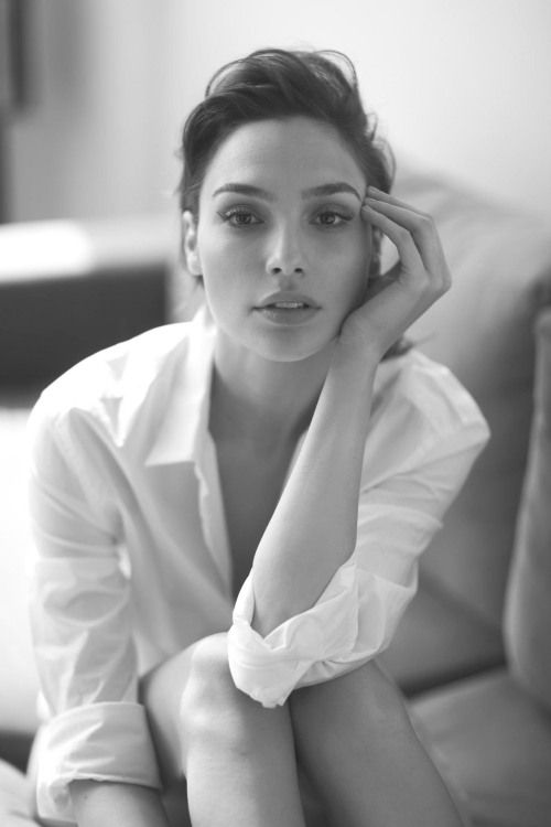 a black and white photo of a woman sitting on a couch with her hand under her chin