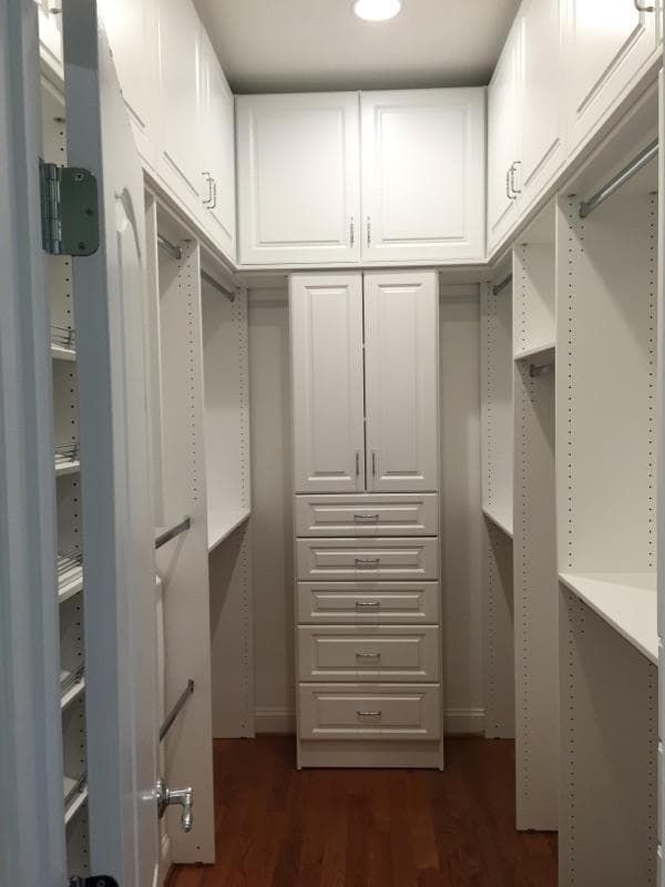 an empty walk in closet with white cabinets