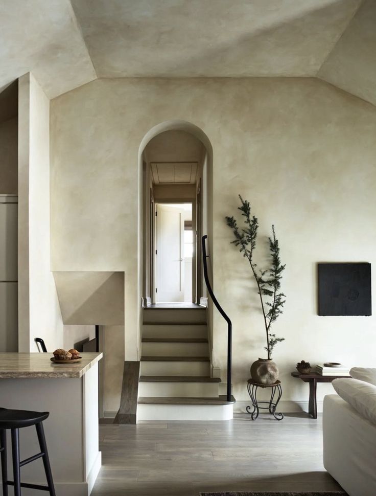 a living room filled with furniture and a stair case next to a kitchen counter top