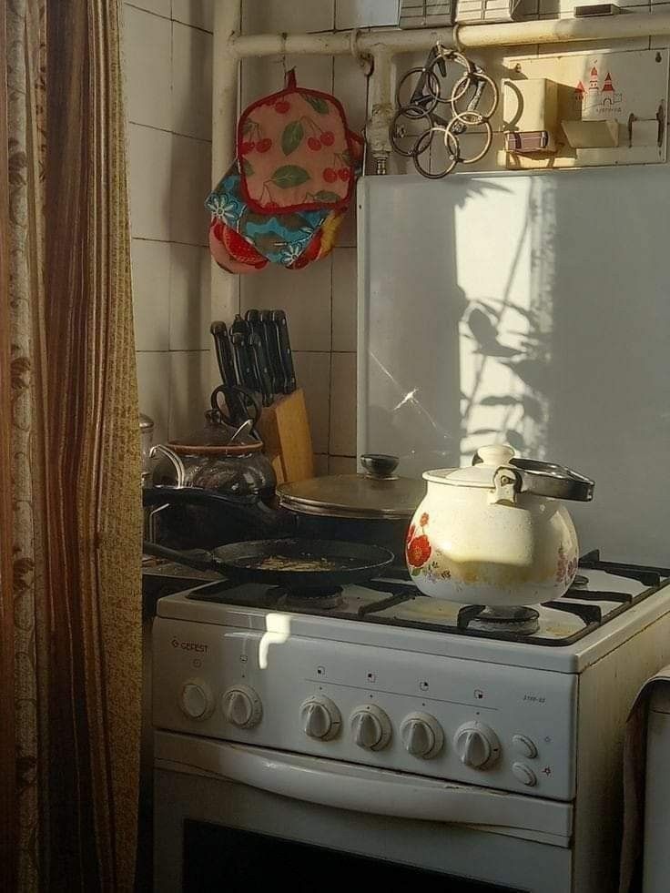 a stove top oven sitting inside of a kitchen next to a wall mounted pot rack