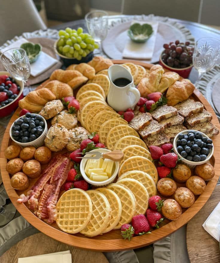 a platter with waffles, strawberries, grapes, and other snacks