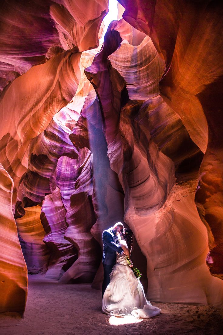 a bride and groom standing in the middle of a slot at antelope canyon