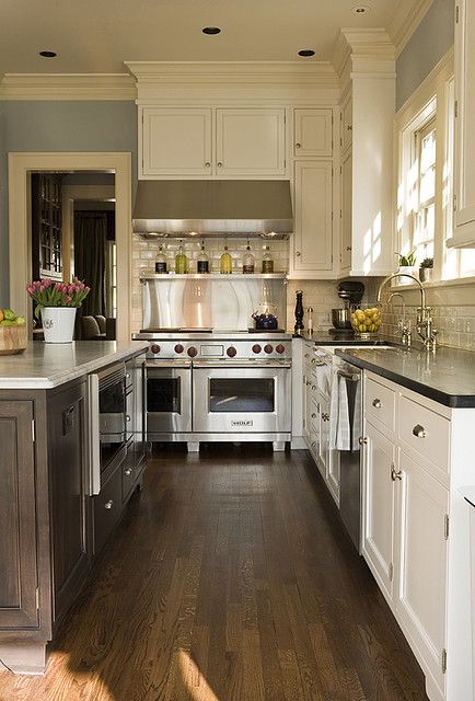 a kitchen with wood floors and white cabinets