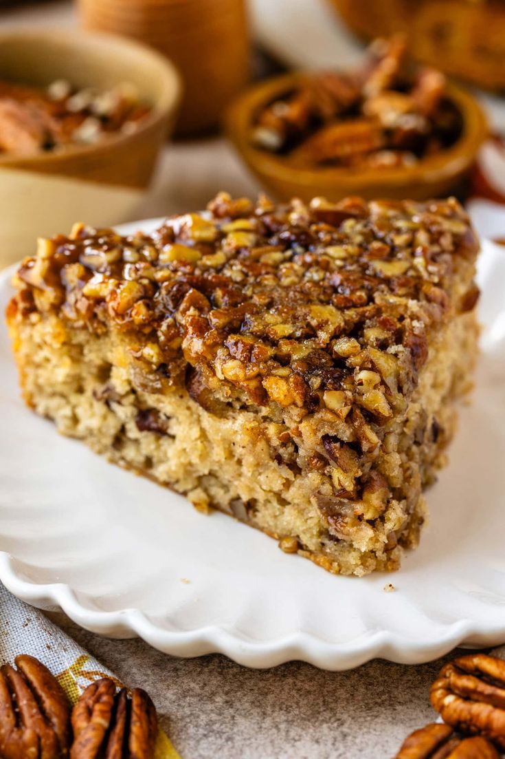 a slice of pecan pie on a white plate with pecans around the edge