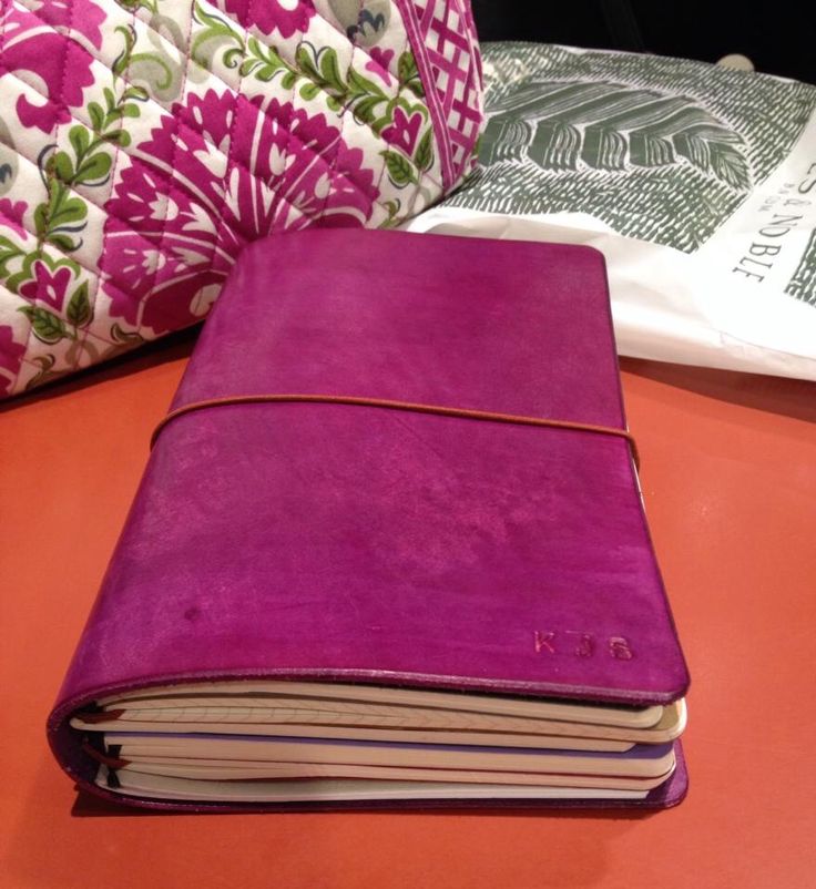 a purple book sitting on top of a table next to pillows and a pillow in the background