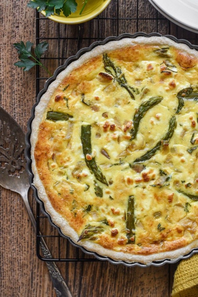 a quiche with asparagus and cheese in a pie pan on a table