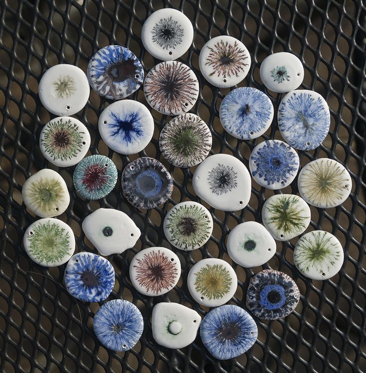 several different kinds of buttons sitting on top of a metal mesh tablecloth covered in blue, green and white flowers