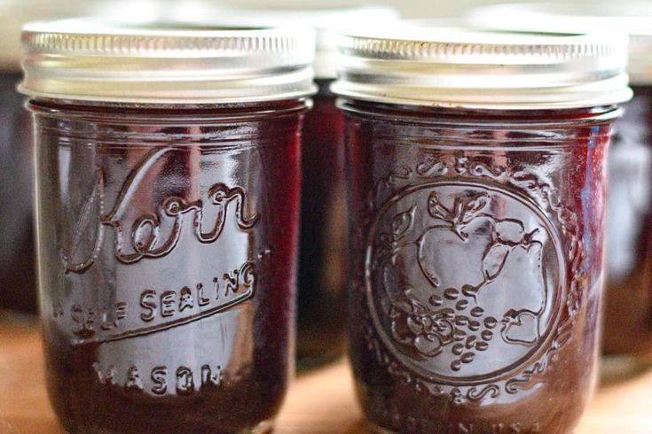 three jars filled with jam sitting on top of a wooden table