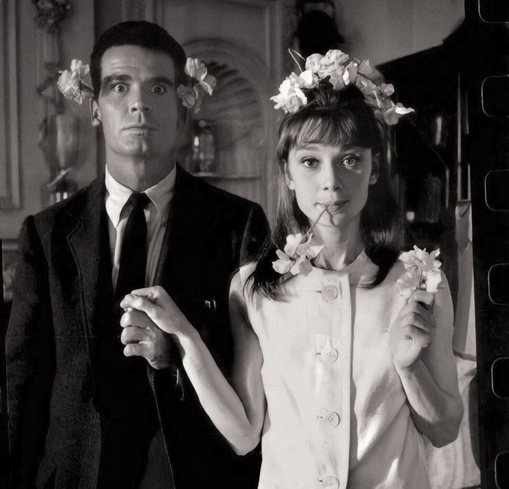 a man and woman standing next to each other with flowers in their hair on their heads