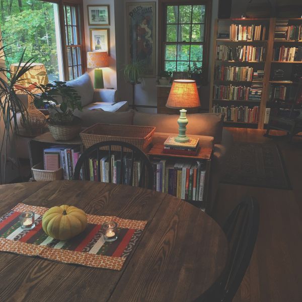 a living room filled with lots of furniture and a wooden table topped with a pumpkin