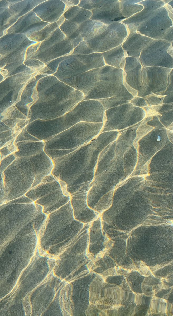 the water is reflecting sunlight on the sand