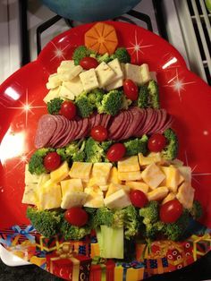 a christmas tree made out of broccoli, cheese and meats on a red plate