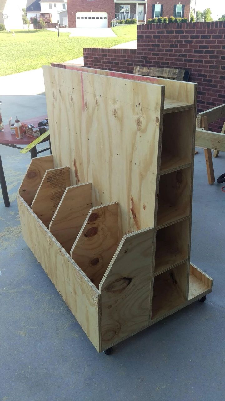 a wooden shelf sitting on top of a cement floor next to a brick wall and building