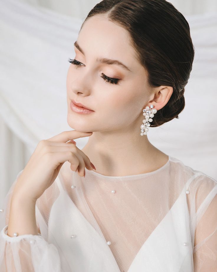 a woman in a white dress is posing for the camera with her hand on her chin