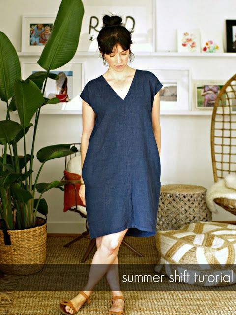 a woman standing in front of a potted plant wearing a blue dress and sandals