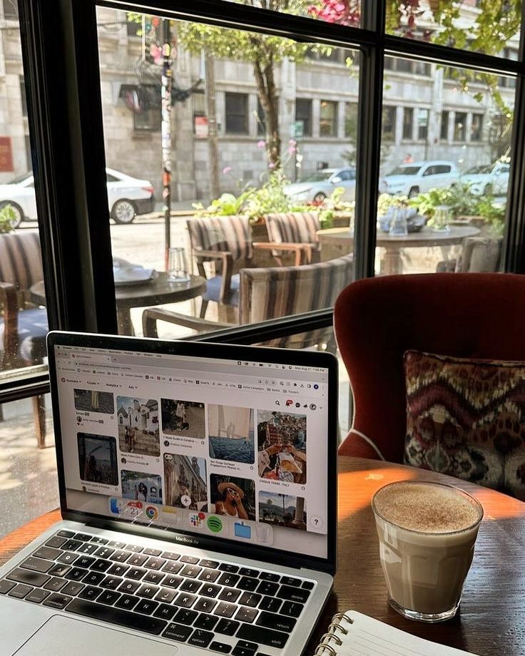 an open laptop computer sitting on top of a wooden table next to a cup of coffee