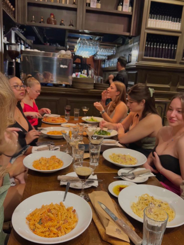 a group of people sitting around a table with plates of food in front of them