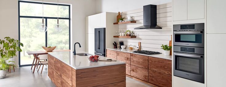 a modern kitchen with wooden cabinets and stainless steel appliances, along with an open floor plan