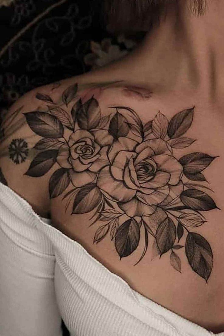 a woman's chest with flowers and leaves tattooed on her upper half - arm