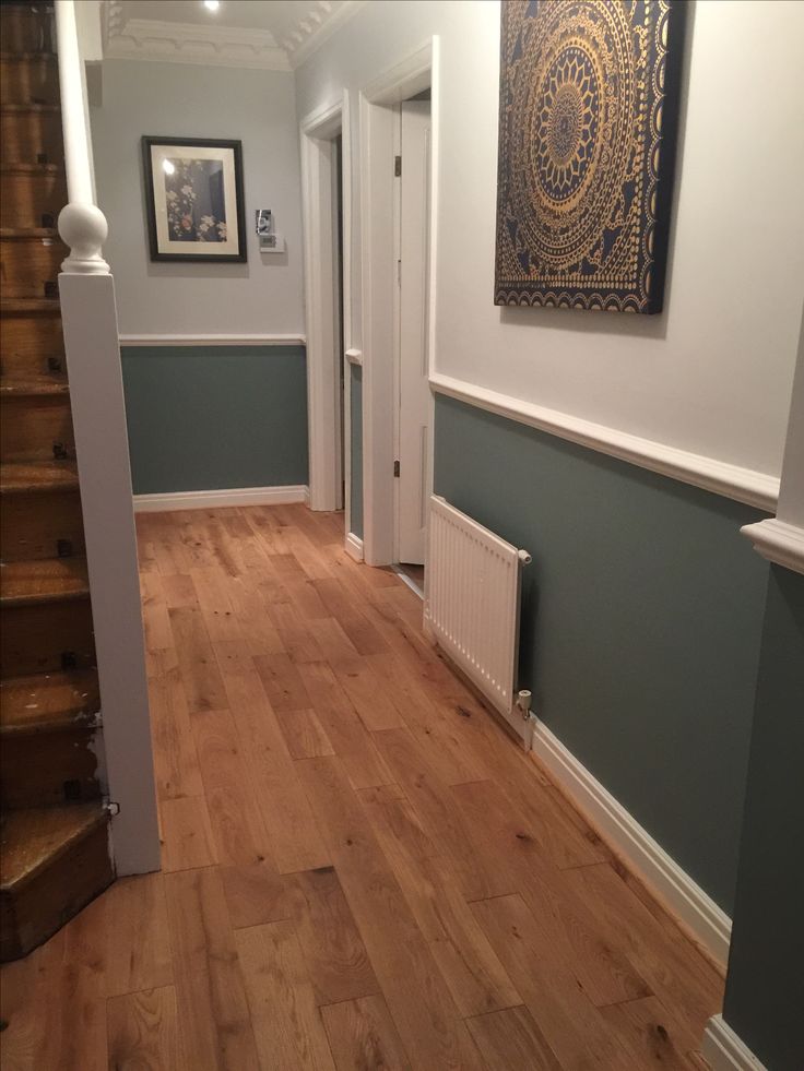 a hallway with hard wood floors and white trim on the walls is painted blue, green and gray