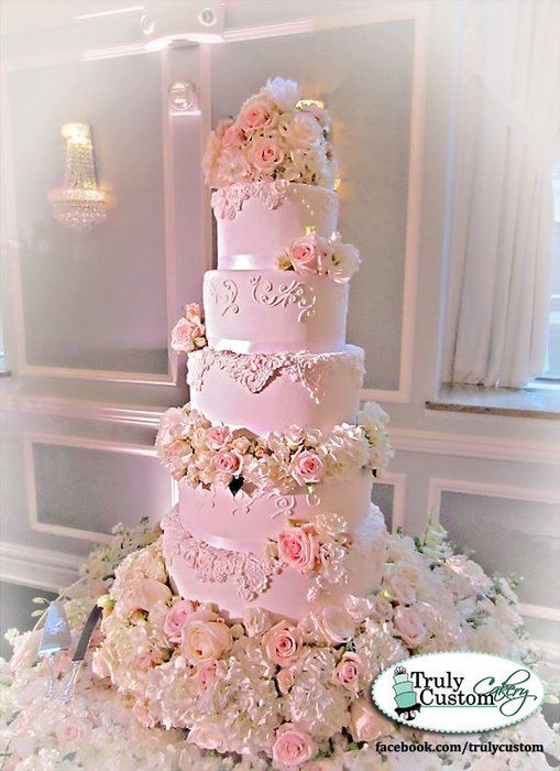 a wedding cake with pink and white flowers on top is surrounded by other floral arrangements