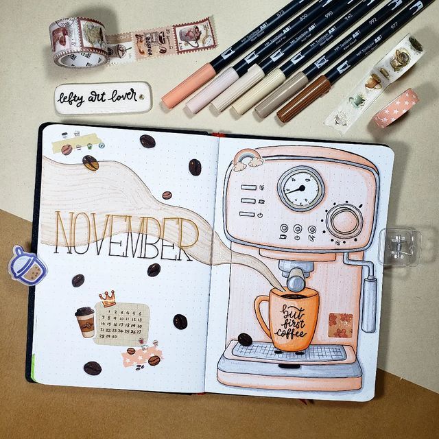 an open notebook with markers and pencils on it next to various items that include coffee maker