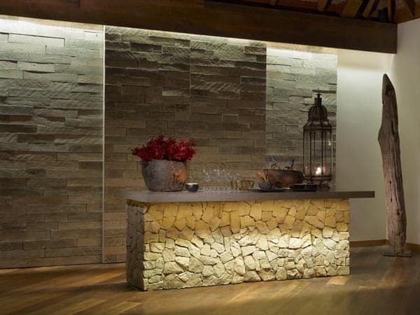 a stone bar with candles and flowers on it in the middle of a wood floored room