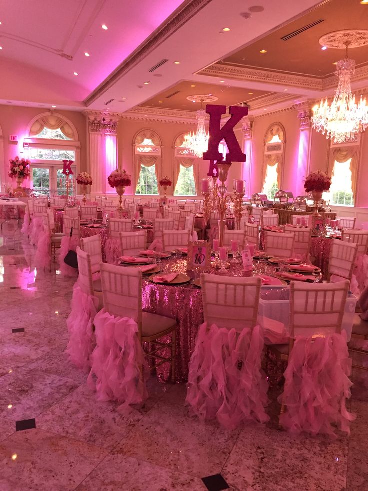 an elegant ballroom with pink lighting and chandeliers on the ceiling, decorated for a wedding