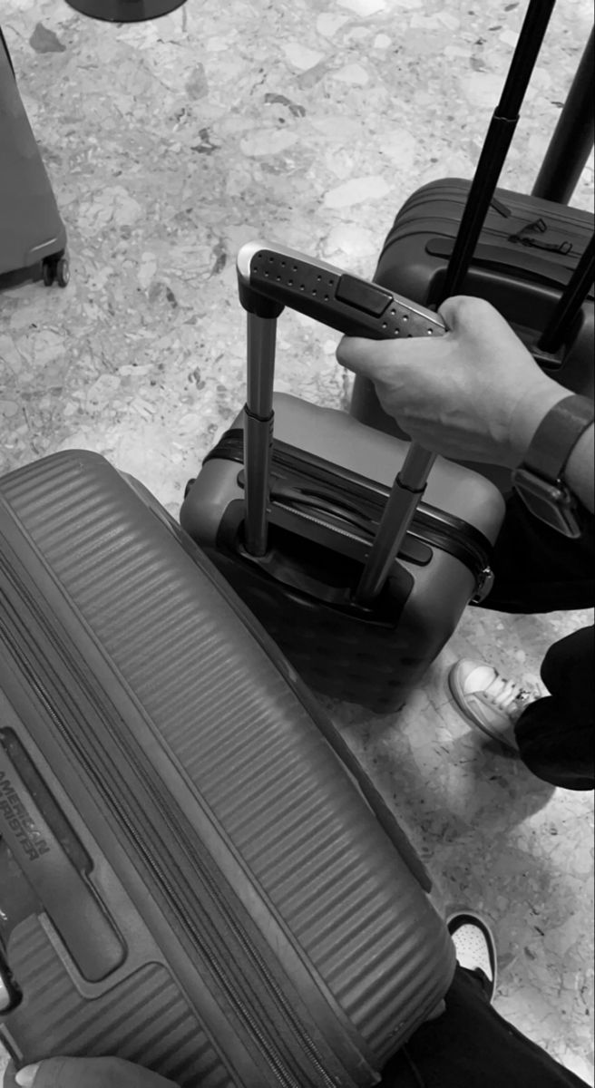 black and white photograph of luggage on the ground with people standing around it looking at them